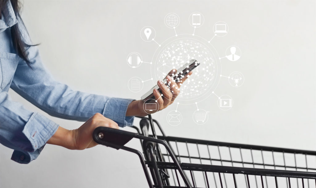 Omnichannel Retail and Grocery Checklist | Worldlink Integration Group | Woman using ominichannel options offered by a grocery or retail business with shopping cart and a unified customer experience