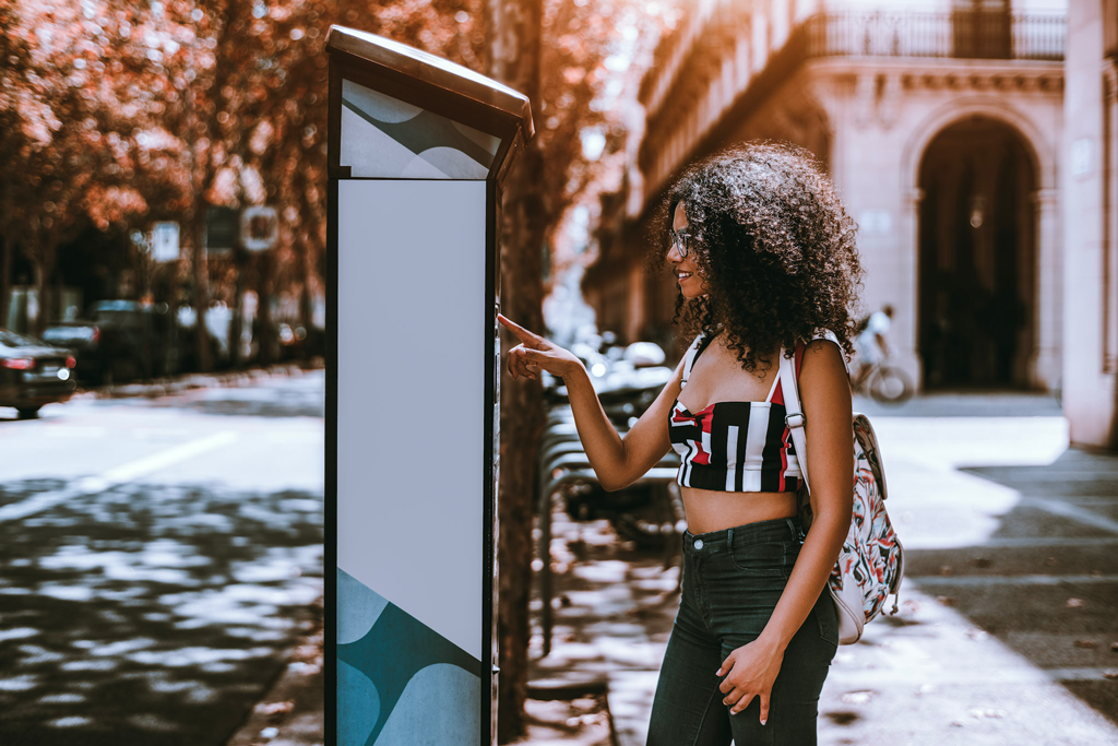 young woman using click and collect kiosk in the middle of a city