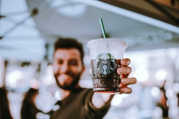IoT things influencing young man buying starbucks and holding drink smiling